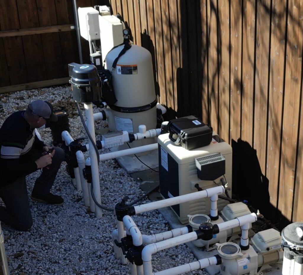 Emerald Pool Care pool repair company employee working on the heating system.