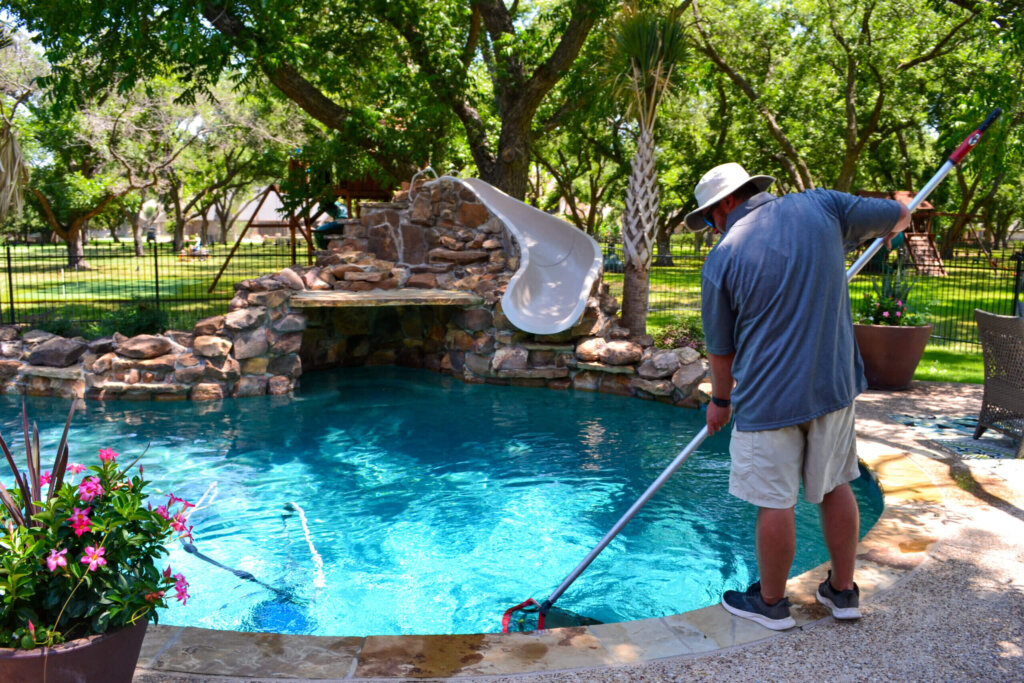 Professional from Emerald Custom Pools using a net while cleaning a pool.