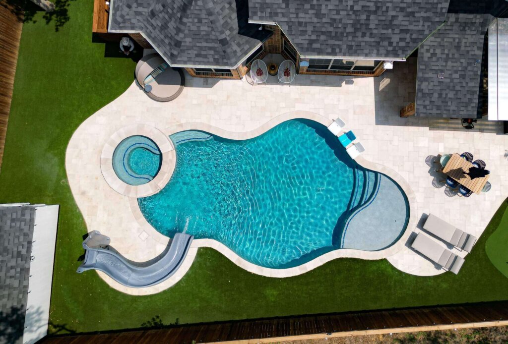 Custom pool with hot tub and slide in pristine condition after resurfacing.