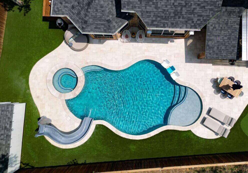 Custom pool with hot tub and slide in pristine condition after resurfacing.